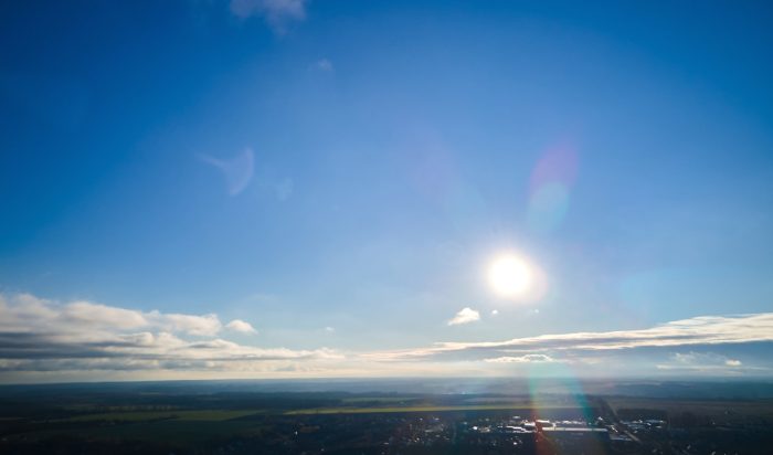 Bright sun light, sunbeams, flares shining through sunrise clouds, cloudscape